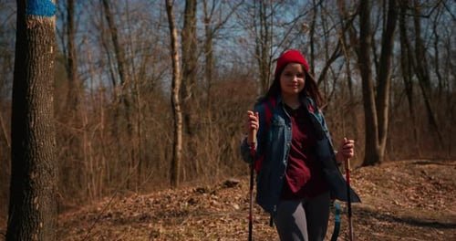 Backpacker Hiker Girl with Hiking Poles Walking Between Trees in a Mountain Forest Hispanic Teenager