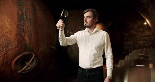 Man Examining Wine in Dark Cellar