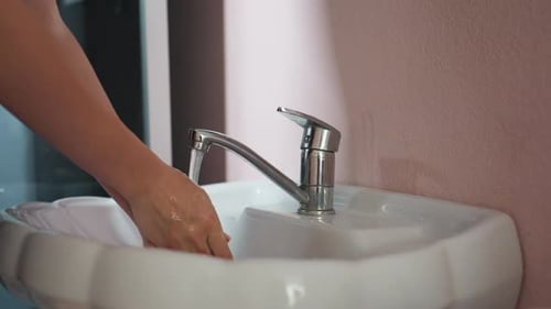 Hands Washing Under Running Faucet in Bathroom
