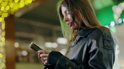 Closeup of a Woman Holding and Using Her Phone While Standing in the City