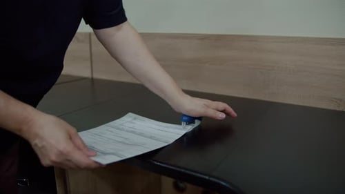 Hand Stamping Documents on Office Desk