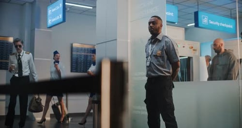 Flight Crew in Airport Terminal Walking with Luggage for Boarding Flight Passing By Security Officer