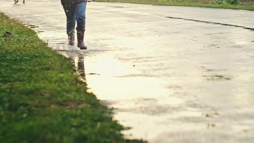 Child Splashing in Puddles on Wet Rural Road