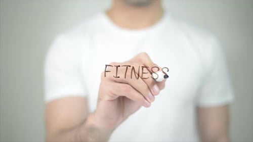 Man Writes the Word Fitness on Clear Surface