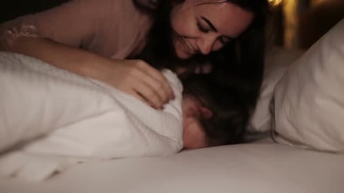 Mother Playfully Wakes Child in Cozy Bedroom