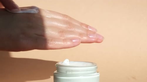 Hands Applying Moisturizer from Jar Close Up