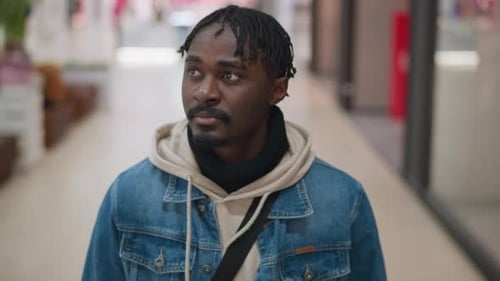 Close Up of Young Man Glancing in Bright Mall Corridor