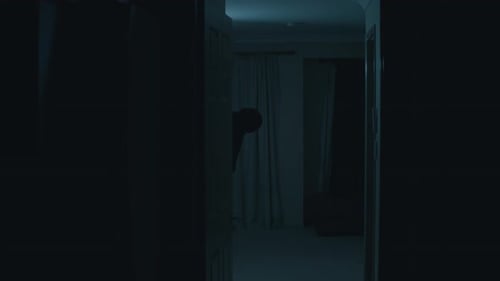 A dark, deformed figure creeps from around a corner and begins curiously staring at the camera befor