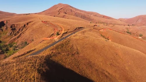 Locals Walk on a Winding Road Crossing the Arid Highlands of Madagascar While an SUV with Tourists