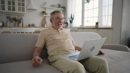 Senior Man Chatting on Laptop in Bright Home