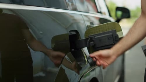 Closeup of Driver Unplugging Electric Car From Charger