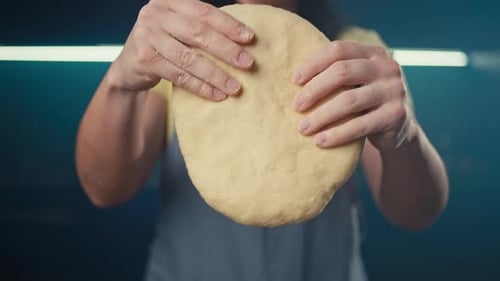 Eine Frau macht mit ihren Händen eine Pizzaform aus dem Teig