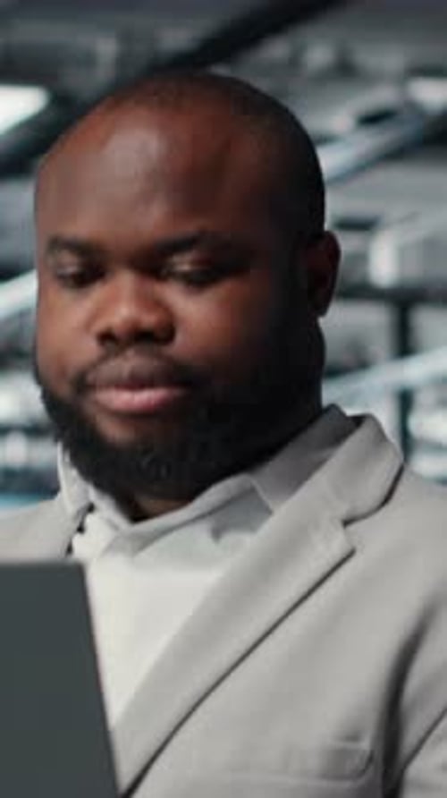 Vertical Video Close Up of Engineer in Server Room Using Laptop Executing Security Patches