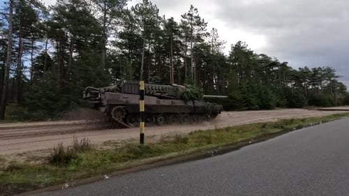Powerful Military Tank Driving Through Muddy Rural Terrain