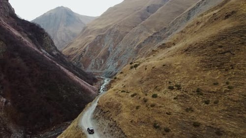 Car Is Riding Winding Road Through a Rugged Mountain Valley