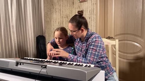Child Learns Piano with Adult's Help