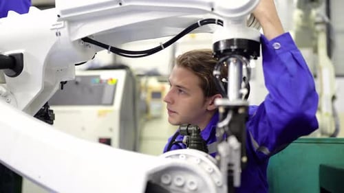 Robotics engineer fitting sensors to traditional engineering Robot Arm in robotics research facility