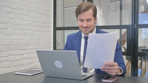 Man Celebrating Success at Desk with Laptop