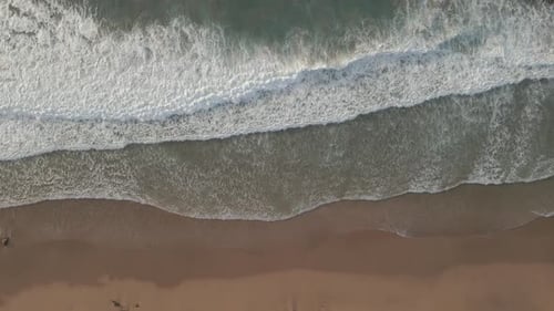 Waves breaking on the beach shore from the air