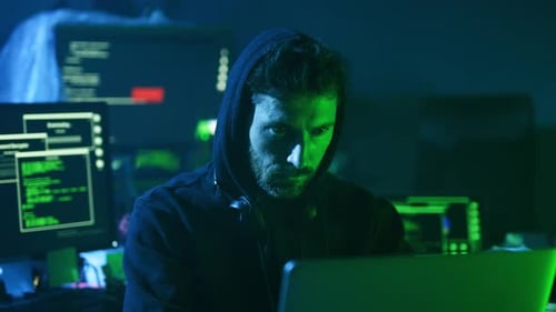 Hooded Man Coding in Dark Room
