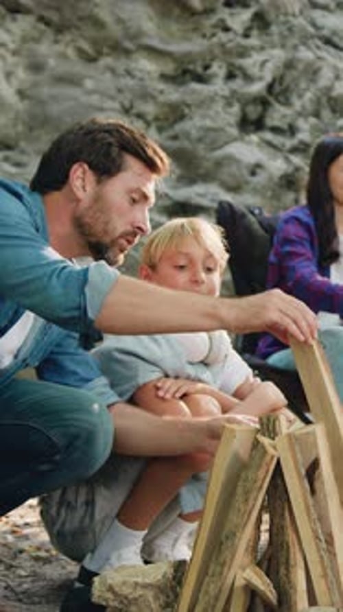 Father and Son Build Campfire Together in Nature