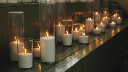 Candlelight Glows from White Candles in Glass Holders
