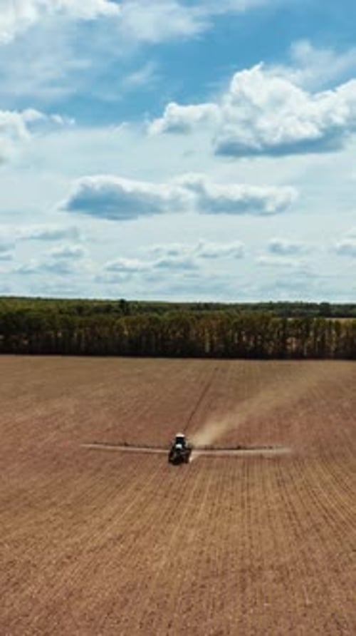 Tractor sprays on field. Aerial view of agricultural sprayer tractor