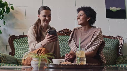 Diverse Girlfriends Looking at Photos on Smartphone in Cafe