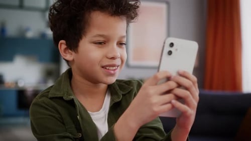 Young Boy Uses Cell Phone Technology in Living Room