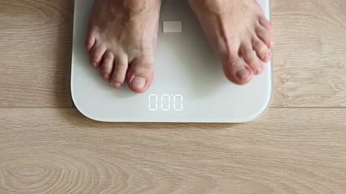 Nahaufnahme eines Mannes, der auf einer Waage läuft, Gewicht misst. Mann geht, BMI überprüft, Gewichtsverlust. Mensch barfuß