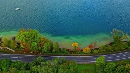 Aerial overview of a car on a road on the coast of lake Attersee, fall in Austria