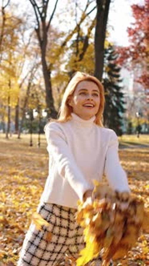Cute Young Woman Swirling with Autumn Leaves Throwing Them in Air and Dancing in Autumn Park Slow