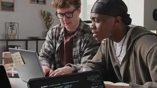 Multiethnische männliche Programmierer programmieren auf einem Laptop und feiern ihren Erfolg