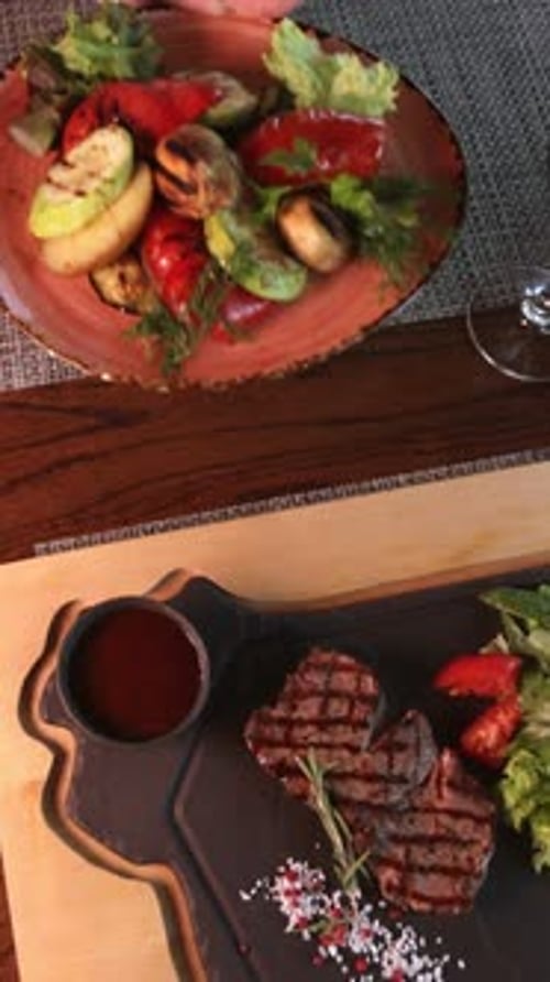Steak on a Plate with Pepper Salt and Vegetables in the Restaurant