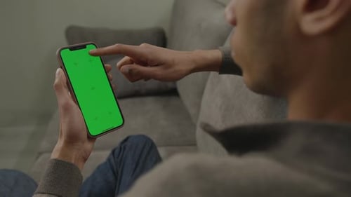 Man Using Smartphone Green Screen Vertically Sitting on Couch Black Male Browsing Vertical Cell