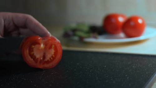 Woman Slices a Red Tomato on Cutting Board
