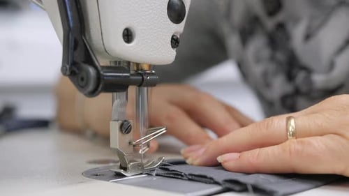 closeup of woman sewing textile on machine, shallow depth of field, slow motion