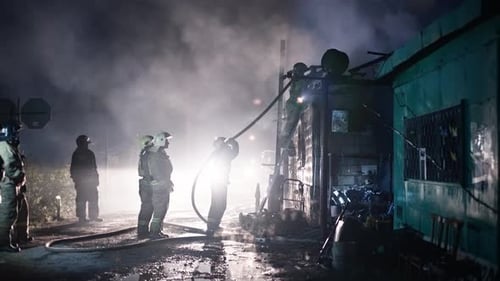 A Team of Firefighters Fights a Fire in an Industrial Area The Fire Hose Delivers Foam to Extinguish