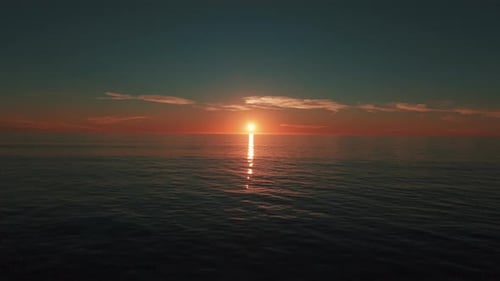 Vue aérienne du coucher de soleil sur l'océan avec une lumière dorée se reflétant sur l'horizon de l'eau créant une soirée calme