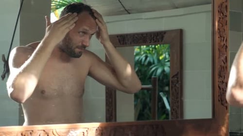 Man styling his hair in front of mirror