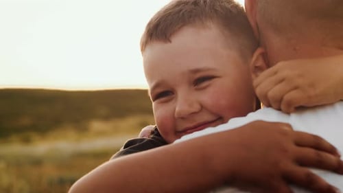 Smiling Boy Hugs Loving Adult at Sunset