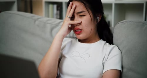 Young Adult Woman Tired and Concerned on Sofa
