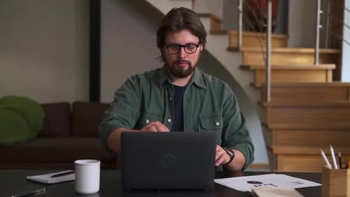 Young Man Opening Laptop and Posing While Sitting at Table in Home Office Spbas