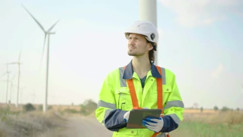 Der Techniker geht einheitlich und schaut sich auf dem Tablet Daten über die Systeminstallation in der Windkraftanlage an