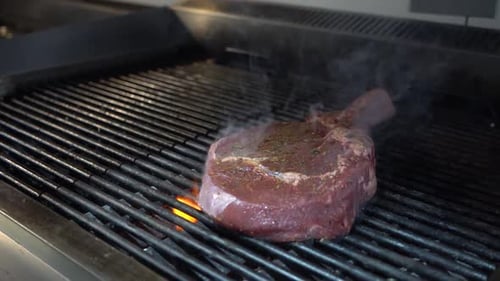 Raw Steak Cooking Over Flames on Grill