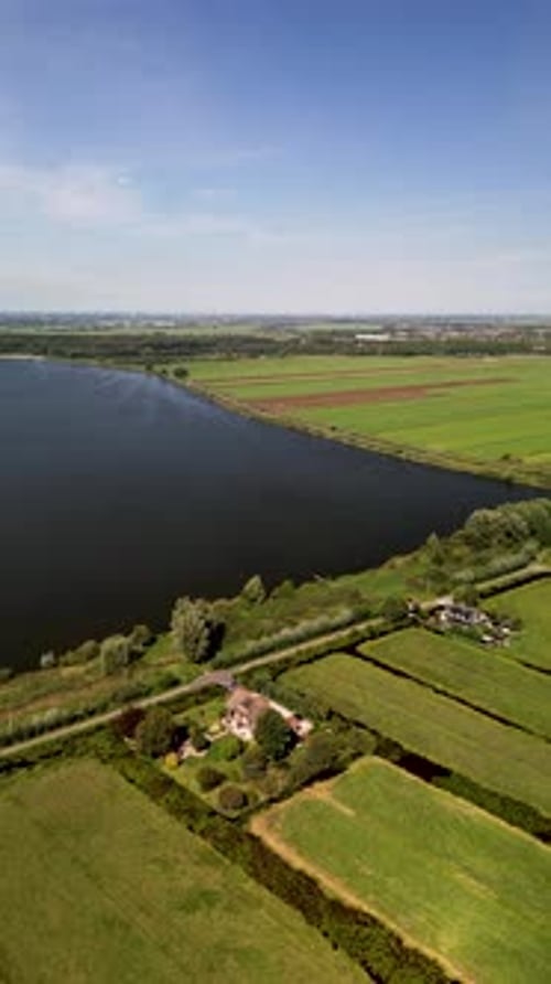 Aerial view of a rural landscape with a central road, water body, irrigated fields