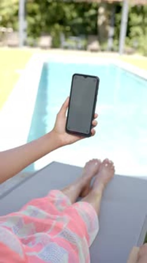 Person Using Cellphone While Relaxing by Pool