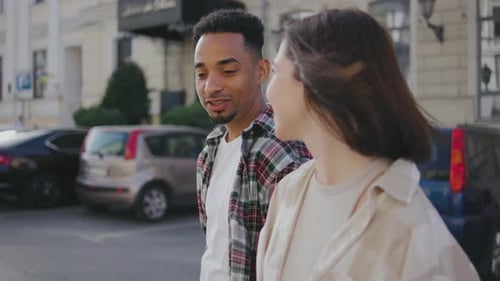 Multiethnic Couple in Love Walks Along the Streets of a European City The Guy and the Girl are Happy
