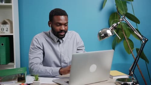 A Dedicated Professional Man Engaged in Working Remotely at His Stylish Home Office Desk