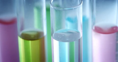 Zeitlupen-Makro von Mikropartikeln, Molekülen in bunten Flüssigkeiten in Röhrchen werden auf ihre Auflösung hin analysiert